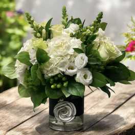 White floral arrangement in a glass vase with green foliage