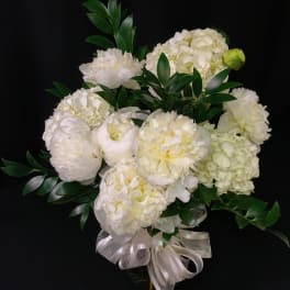 White floral bouquet with green foliage and a ribbon bow