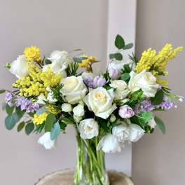 Bouquet of white roses and yellow filler flowers in a glass vase