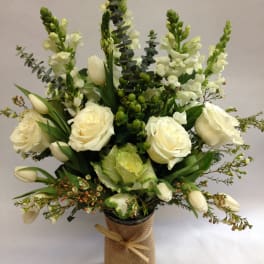 White roses and tulips arranged in a burlap-wrapped vase