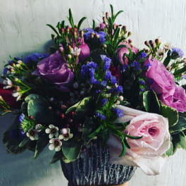 Bouquet of pink and purple roses with small white flowers in a vase