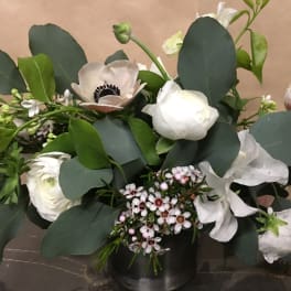 White anemones and ranunculus in a low black vase