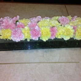 Pink and yellow carnations arranged in a long rectangular container