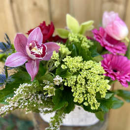 Mixed bouquet with pink orchids, magenta blooms, and green hydrangea in a vase