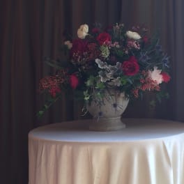 Large floral arrangement in a stone urn on a draped table