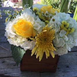 Yellow roses and white hydrangeas in a wooden box