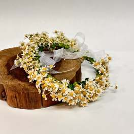 Daisy flower crown with white ribbon on a wooden stand