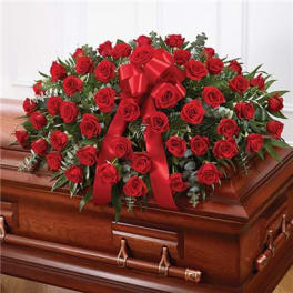 Red rose casket spray with a satin ribbon on a wooden casket