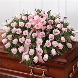 Pink rose casket spray with ribbon on a wooden casket