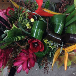 Tropical bouquet with red, pink, and yellow flowers and glossy green leaves