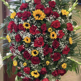 Large standing spray of red roses, yellow sunflowers, and white gladiolus