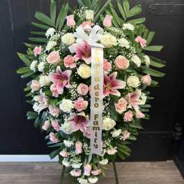 Large pink and white funeral wreath on an easel with a ribbon