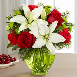 Red roses and white lilies arranged in a green glass vase.