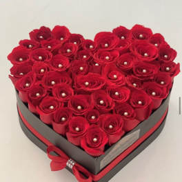 Heart-shaped box filled with red roses and pearl accents