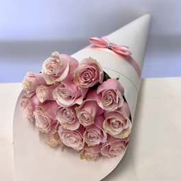 Bouquet of pale pink roses wrapped in white paper with a pink ribbon