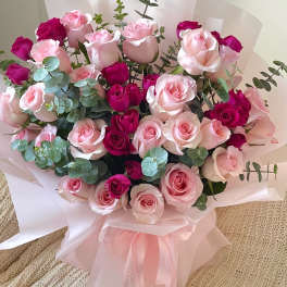 Bouquet of pink and magenta roses wrapped in pale pink paper