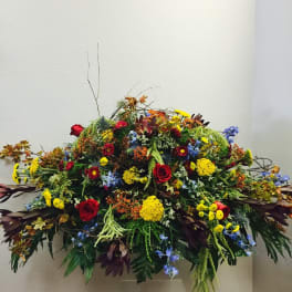 Large cascading arrangement of red, yellow, and blue flowers in an asymmetrical display.