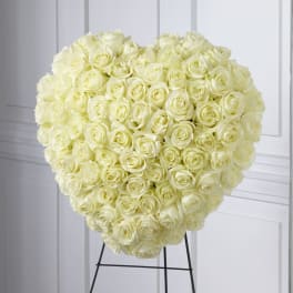Heart-shaped arrangement of ivory roses on a black metal easel stand