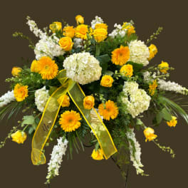 Yellow roses and white hydrangeas in a large standing spray with a yellow ribbon