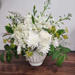 White floral arrangement in a white vase with roses and daisies