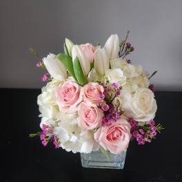 Pink and white rose bouquet with white lilies in a glass vase