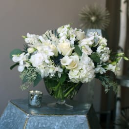 White floral bouquet in a glass vase on a blue pedestal