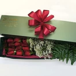 Box of red roses with baby's breath and greenery tied with a red ribbon