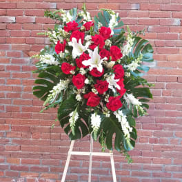 Standing floral spray of red roses and white lilies on an easel