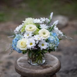 White and blue flower arrangement in a clear glass vase