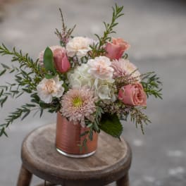Pink and white bouquet in a copper vase on a stool