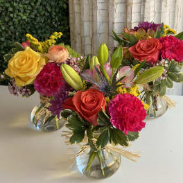 Three colorful mixed flower arrangements in clear glass vases