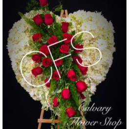 Heart-shaped standing spray of red roses and white flowers on an easel