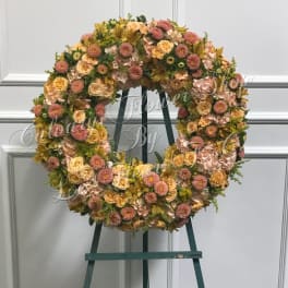 Large floral wreath on an easel with pink and peach blooms