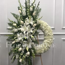 White funeral spray with lilies, roses, and a hydrangea wreath