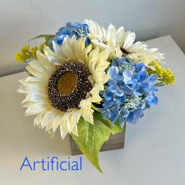 Artificial sunflower and blue hydrangea arrangement in a small wooden container