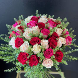 Bouquet of red, pink, and blush roses with airy greenery