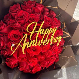 Bouquet of red roses with a gold Happy Anniversary topper