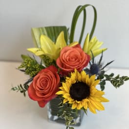 Bouquet of orange roses and a sunflower in a glass vase