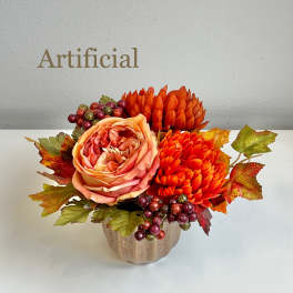 Artificial floral arrangement with orange blooms in a small vase