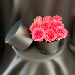 Pink roses in a black round box with the lid leaning beside it