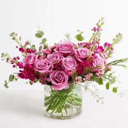 Pink roses arranged in a clear glass vase with small magenta filler flowers