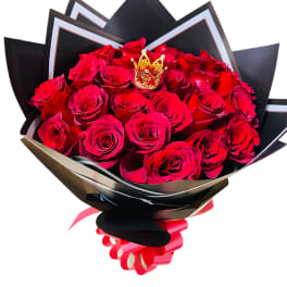 Bouquet of red roses wrapped in black paper with a gold crown accent