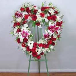 Heart-shaped floral wreath on a standing easel with red, white, and pink flowers