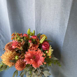 Mixed bouquet of pink, orange, and yellow flowers with greenery