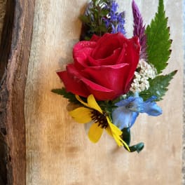 Boutonniere with a red rose and small blue, yellow, and purple flowers