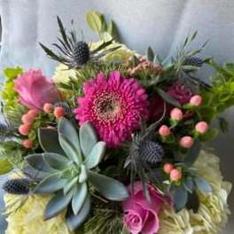 Bouquet of pink gerbera daisies and roses with blue thistle-like blooms
