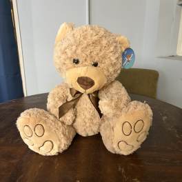 Plush teddy bear with a brown ribbon sitting on a table