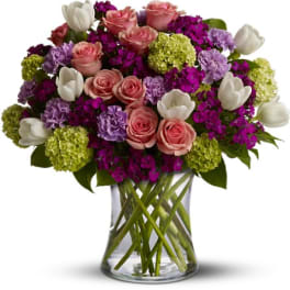Pink roses, white tulips, and purple flowers in a clear glass vase