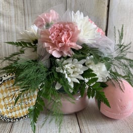 Pink and white flower arrangement with a candle tin and pink bath bomb