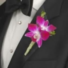 Pink orchid boutonniere pinned to a black suit jacket